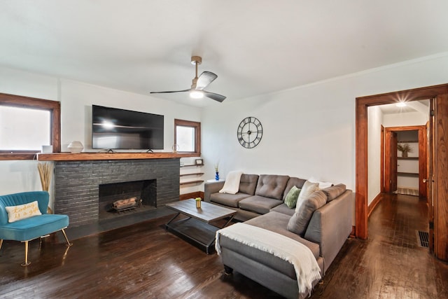 living area featuring a brick fireplace, ceiling fan, visible vents, ornamental molding, and wood finished floors