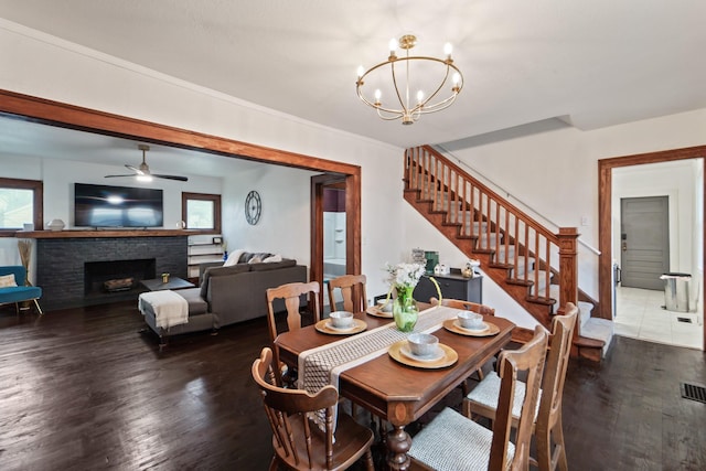 dining space with a wealth of natural light, wood finished floors, ceiling fan with notable chandelier, and stairs