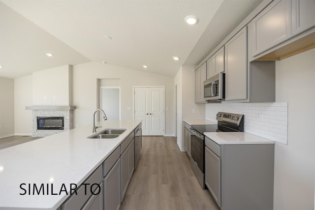 9394 Modena Ln, West Des Moines, IA 50266 - kitchen featuring appliances with stainless steel finishes, gray cabinets, light wood-type flooring, backsplash, and light countertops