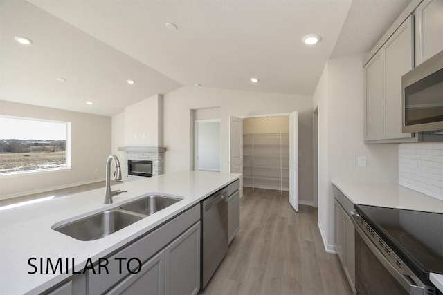 9394 Modena Ln, West Des Moines, IA 50266 - kitchen with appliances with stainless steel finishes, light wood-style flooring, a glass covered fireplace, light countertops, and gray cabinetry
