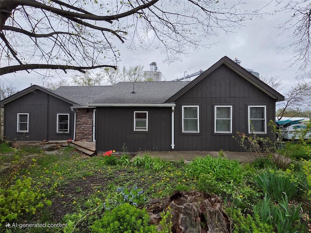 rear view of house featuring a shingled roof, a chimney, and stone siding