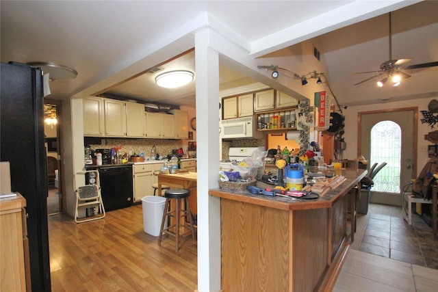 kitchen featuring a ceiling fan, backsplash, visible vents, black appliances, and light wood-style flooring
