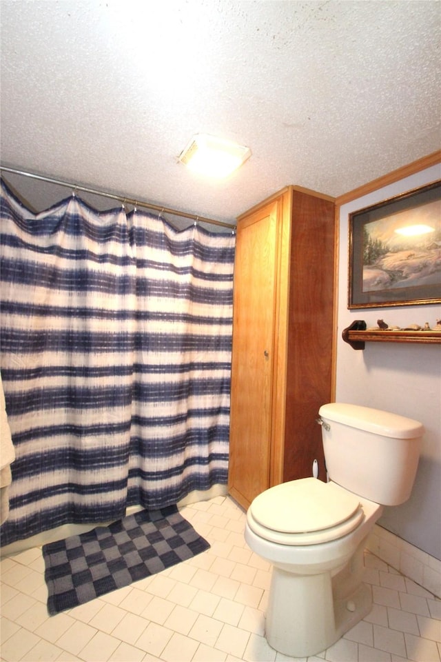 bathroom featuring a textured ceiling, a shower with shower curtain, tile patterned floors, and toilet