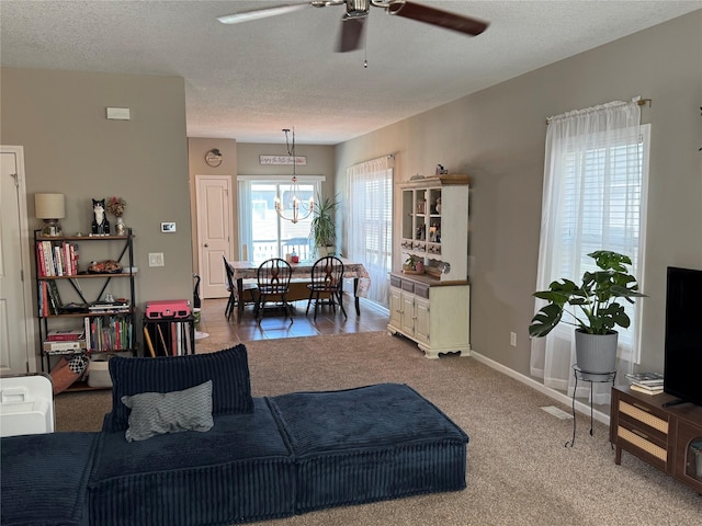 223 SE Booth Ave, Waukee, IA 50263 - carpeted living area featuring a textured ceiling, baseboards, and ceiling fan with notable chandelier