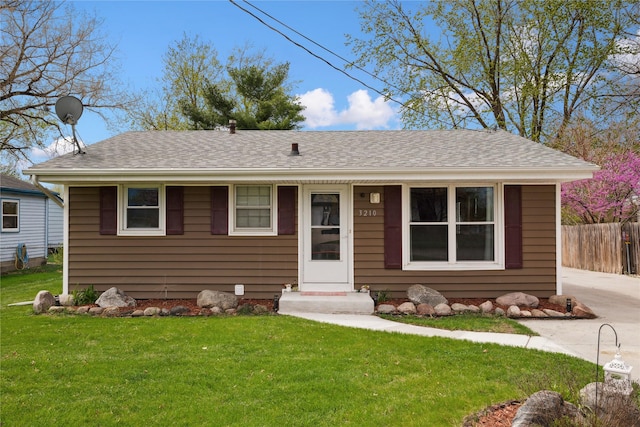 view of front of property with a front yard, a shingled roof, and fence