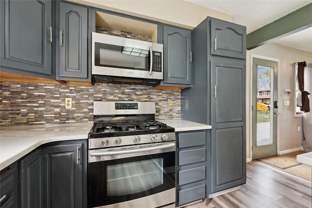 kitchen featuring gray cabinets, backsplash, stainless steel appliances, and light wood-style floors