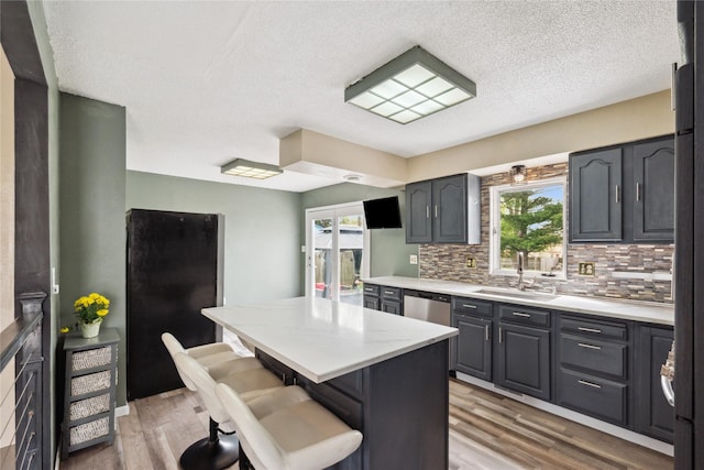 kitchen featuring a center island, decorative backsplash, light wood-style flooring, and a sink
