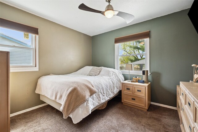 bedroom with ceiling fan, dark carpet, and baseboards