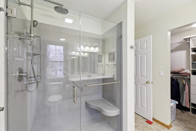 full bathroom with a walk in closet, a stall shower, and a textured ceiling