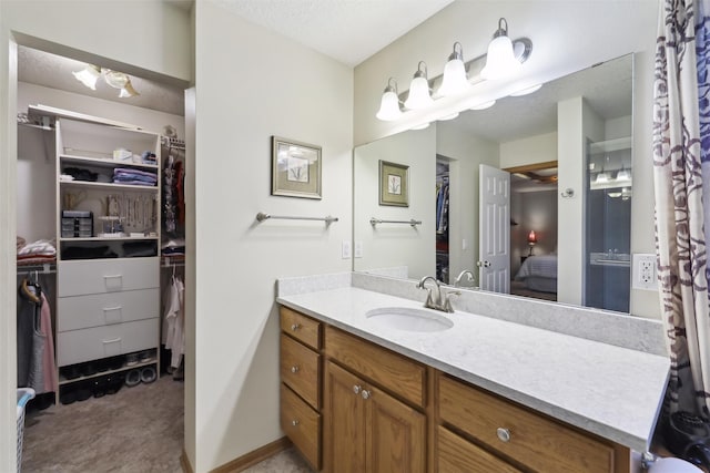 ensuite bathroom with connected bathroom, baseboards, vanity, and a spacious closet