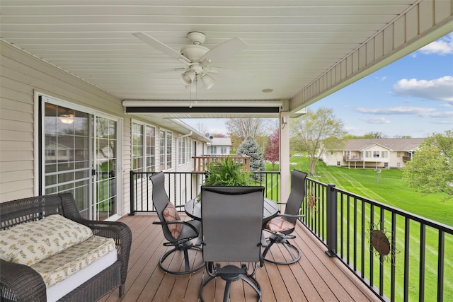 deck with ceiling fan, outdoor dining space, and a yard