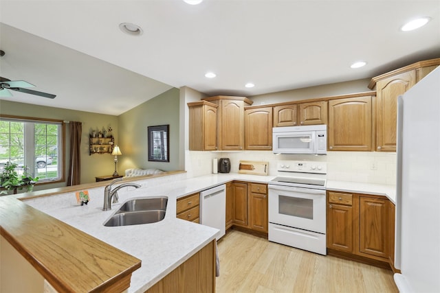 kitchen featuring white appliances, light countertops, backsplash, a sink, and a peninsula