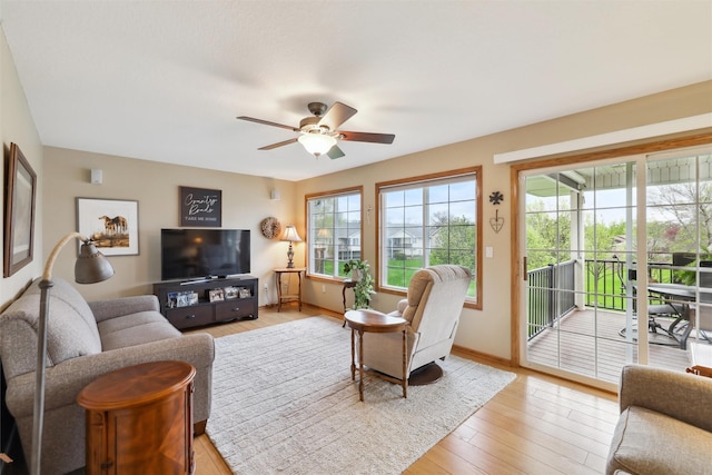 living area with ceiling fan, baseboards, and light wood-style floors