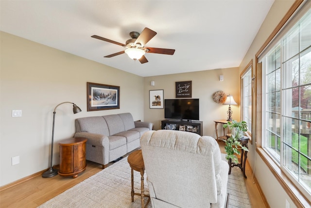 living room featuring baseboards, a ceiling fan, and light wood-style floors