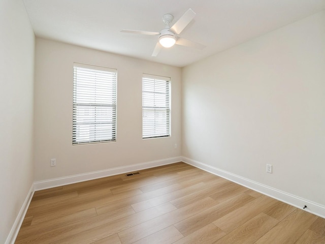 unfurnished room with visible vents, a ceiling fan, light wood finished floors, and baseboards