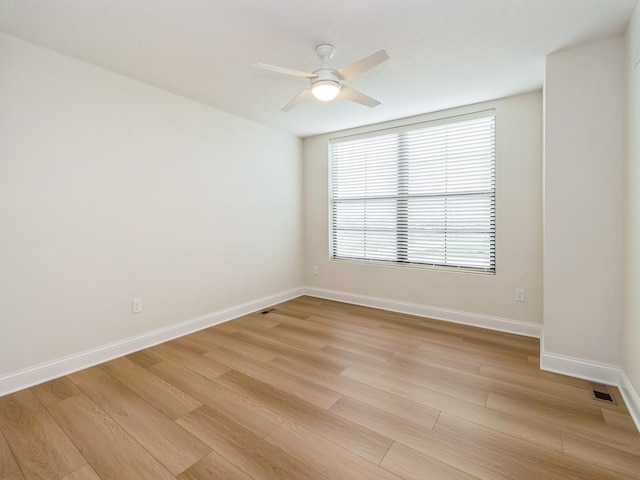 spare room featuring visible vents, ceiling fan, light wood-style flooring, and baseboards