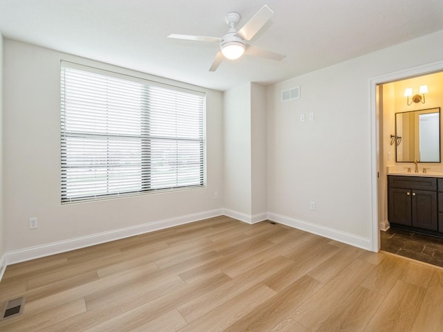 interior space with visible vents, connected bathroom, light wood finished floors, and a sink
