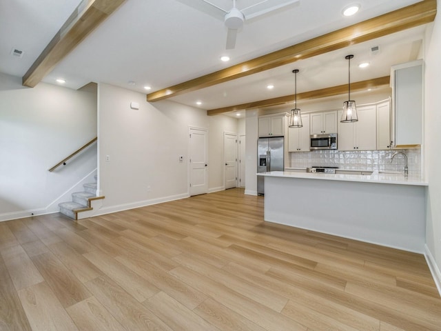 kitchen featuring appliances with stainless steel finishes, beam ceiling, light countertops, and baseboards