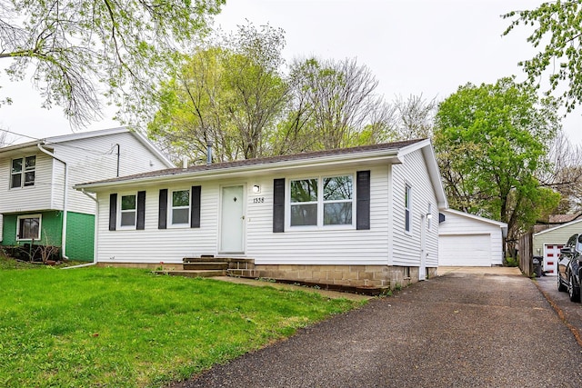 tri-level home with entry steps, an outdoor structure, a front lawn, and a garage