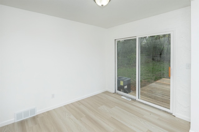 unfurnished room featuring visible vents, baseboards, and wood finished floors