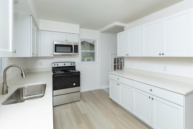 kitchen with light countertops, stainless steel microwave, a sink, and electric stove