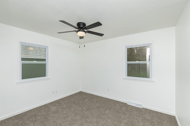 spare room with visible vents, a ceiling fan, baseboards, and dark colored carpet