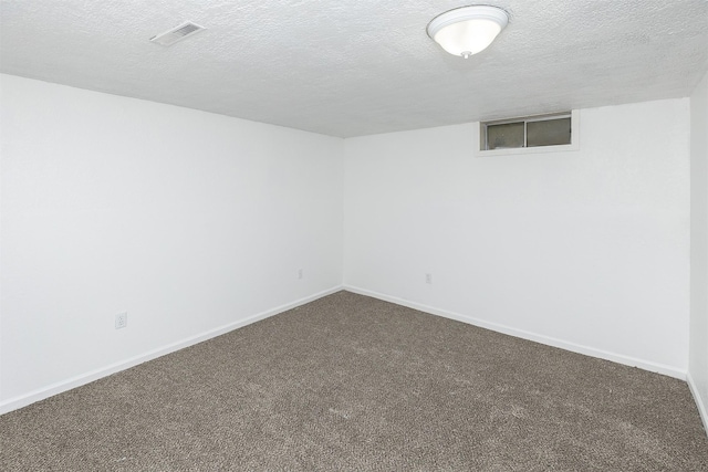 empty room with visible vents, a textured ceiling, baseboards, and dark colored carpet