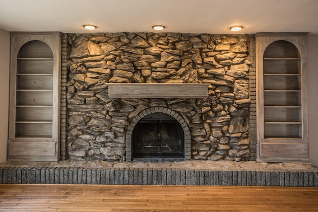 details with a stone fireplace and wood finished floors