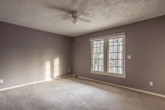 empty room featuring a textured ceiling, a ceiling fan, carpet flooring, and baseboards