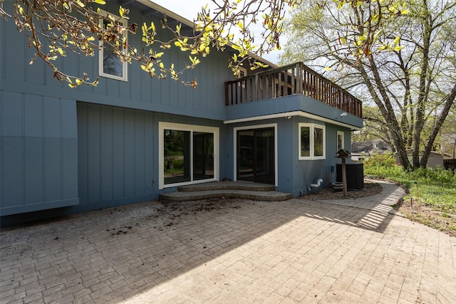 rear view of house featuring a patio area, central air condition unit, and a balcony