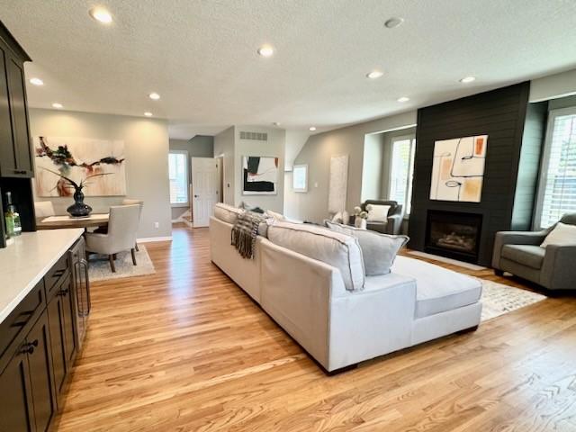 601 41st St, Des Moines, IA 50312 - living room featuring recessed lighting, light wood finished floors, a large fireplace, healthy amount of natural light, and a textured ceiling