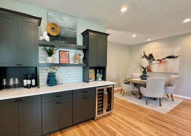 601 41st St, Des Moines, IA 50312 - indoor dry bar featuring wine cooler, light wood-type flooring, backsplash, a textured ceiling, and recessed lighting