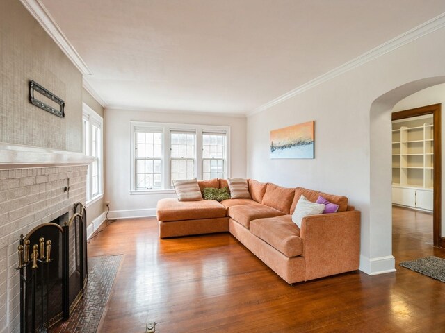 322 49th St, Des Moines, IA 50312 - living room featuring dark wood-style flooring, arched walkways, ornamental molding, a fireplace, and baseboards