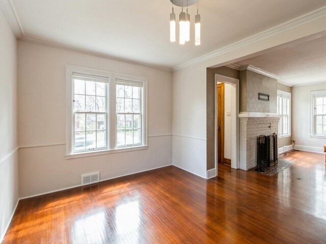 322 49th St, Des Moines, IA 50312 - unfurnished living room featuring wood finished floors, a chandelier, a brick fireplace, baseboards, and crown molding