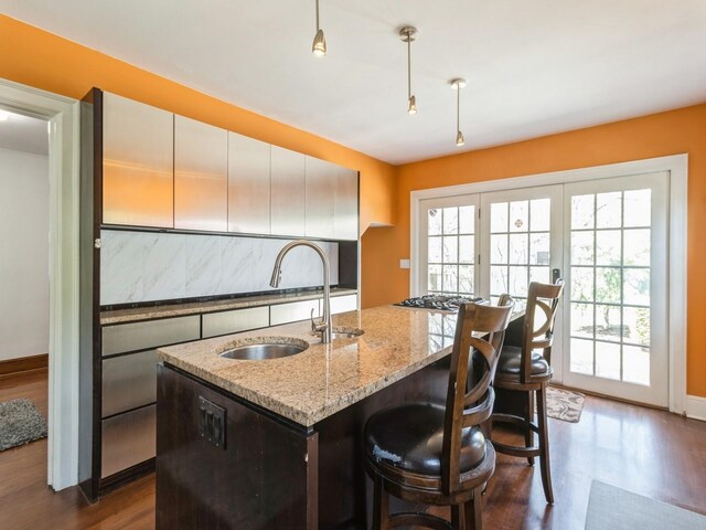322 49th St, Des Moines, IA 50312 - kitchen featuring a sink, dark wood-style flooring, light stone countertops, an island with sink, and baseboards