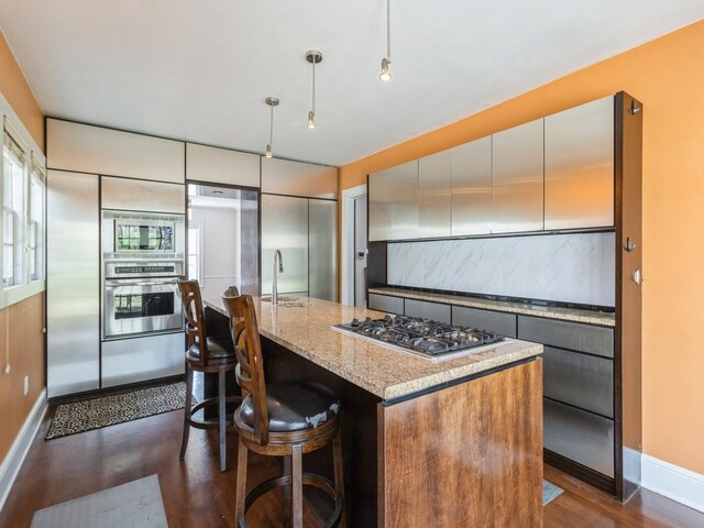 322 49th St, Des Moines, IA 50312 - kitchen with stainless steel appliances, dark wood-style flooring, baseboards, and light stone countertops