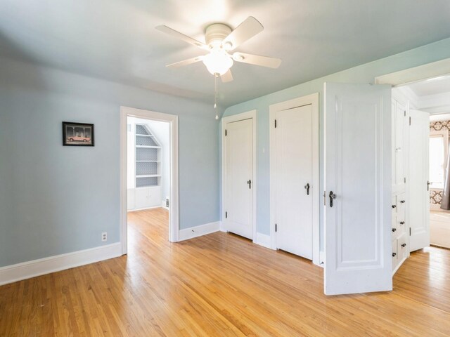 322 49th St, Des Moines, IA 50312 - unfurnished bedroom with two closets, light wood finished floors, baseboards, connected bathroom, and ceiling fan