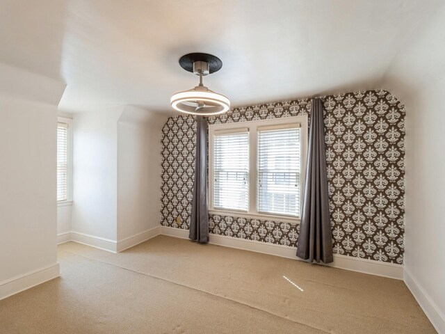 322 49th St, Des Moines, IA 50312 - unfurnished dining area with carpet, baseboards, healthy amount of natural light, vaulted ceiling, and wallpapered walls
