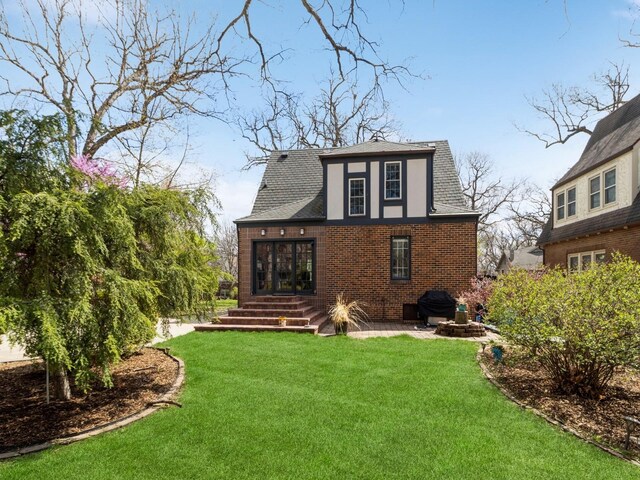 322 49th St, Des Moines, IA 50312 - rear view of property featuring roof with shingles, brick siding, and a yard