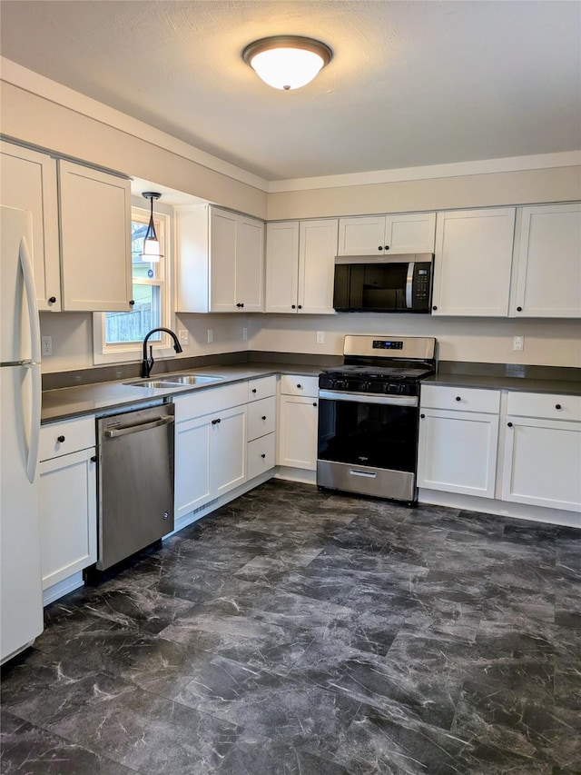 1300 NE 50th Pl, Des Moines, IA 50313 - kitchen featuring stainless steel appliances, dark countertops, white cabinetry, and hanging light fixtures