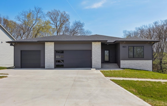 prairie-style home with a shingled roof, driveway, and an attached garage