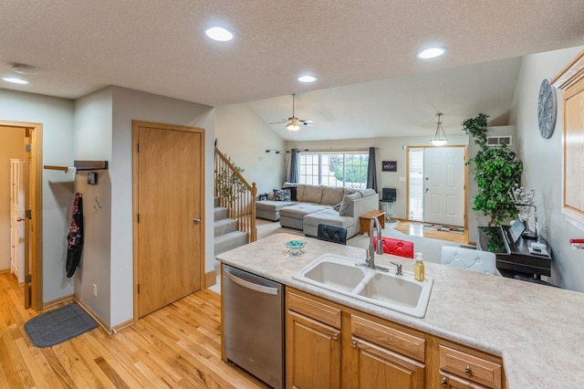 kitchen with a textured ceiling, dishwasher, a sink, light countertops, and light wood-style floors