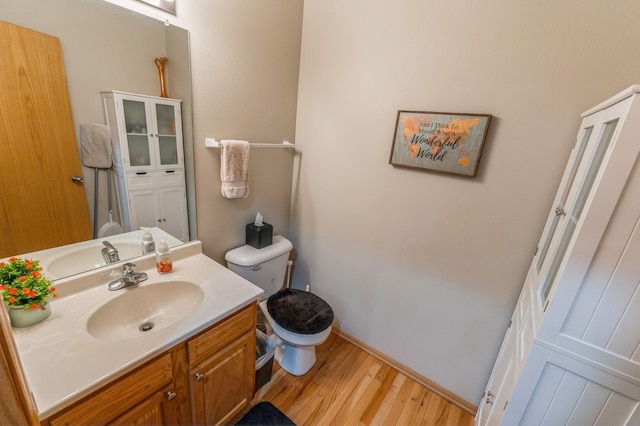 bathroom featuring baseboards, vanity, toilet, and wood finished floors