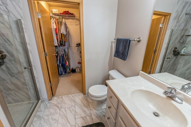 bathroom with vanity, toilet, marble finish floor, a shower stall, and a spacious closet