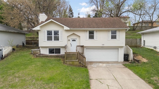bi-level home with fence, a garage, a front yard, a chimney, and driveway