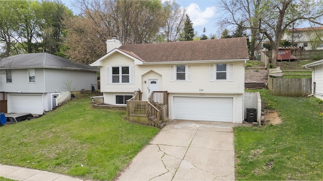 bi-level home featuring concrete driveway, an attached garage, a chimney, and a front yard