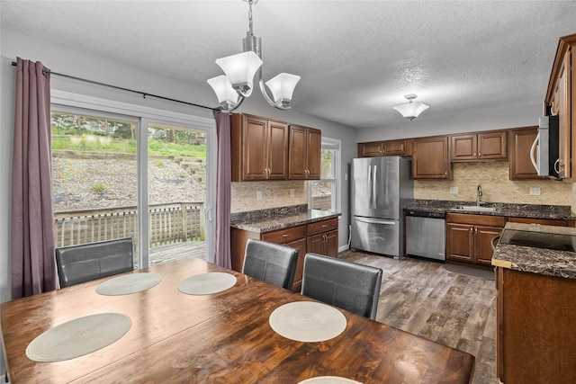 kitchen featuring dark wood-style flooring, a sink, a textured ceiling, stainless steel appliances, and backsplash