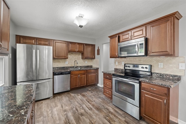 kitchen featuring brown cabinets, appliances with stainless steel finishes, a sink, and wood finished floors