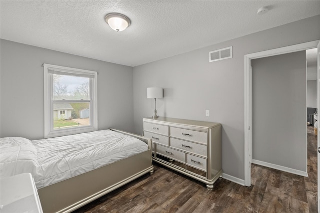 bedroom featuring dark wood-style flooring, a textured ceiling, visible vents, and baseboards