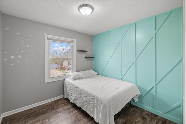 bedroom with baseboards, a textured ceiling, and dark wood-style flooring